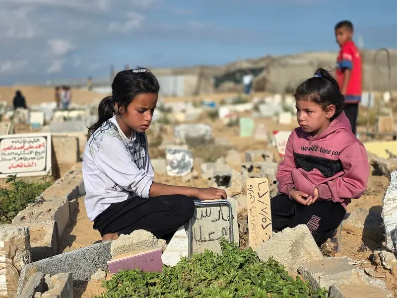 Durante el primer d&iacute;a del Eid al-Adha (Fiesta del Cordero) unas ni&ntilde;as palestinas visitan las tumbas de sus padres, asesinados durante el genocidio, en un cementerio de Jan Yunis, 27 de mayo de 2026 - Tariq Mohammad / APA Images.