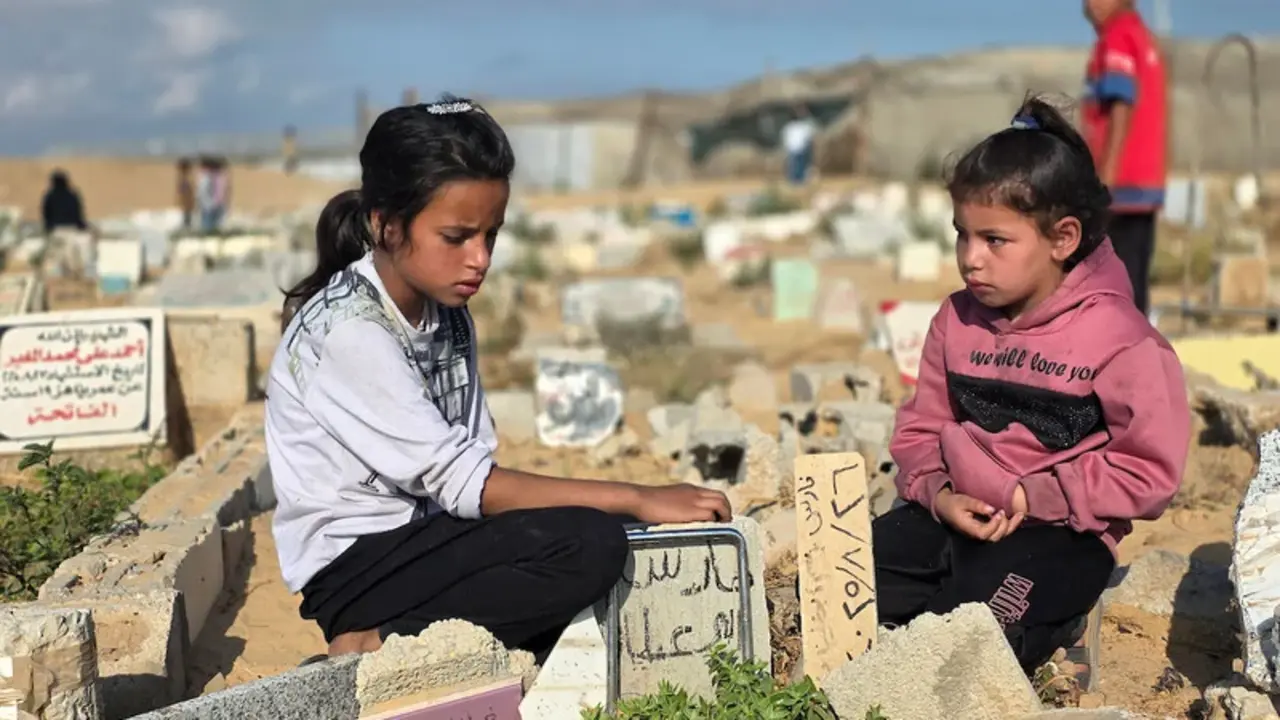 Durante el primer d&iacute;a del Eid al-Adha (Fiesta del Cordero) unas ni&ntilde;as palestinas visitan las tumbas de sus padres, asesinados durante el genocidio, en un cementerio de Jan Yunis, 27 de mayo de 2026 - Tariq Mohammad / APA Images.