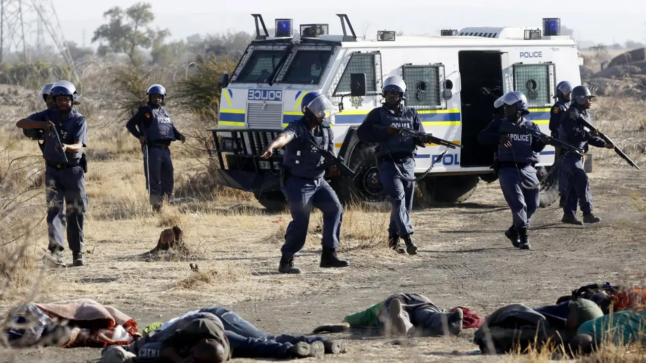 Un polic&iacute;a gesticula frente a los cuerpos de algunos de los treinta y cuatro mineros asesinados el 16 de agosto de 2012 por la polic&iacute;a sudafricana en la mina de platino de la empresa Lonmin situada en Marikana (Rustenburg, North West Province), durante la presidencia de Jacob Zuma. El director de Lonmin, adem&aacute;s de accionista de la empresa, en ese momento era Cyril Ramaphosa, actual presidente de Sud&aacute;frica &ndash; South African History Online / Siphiwe Sibeko.